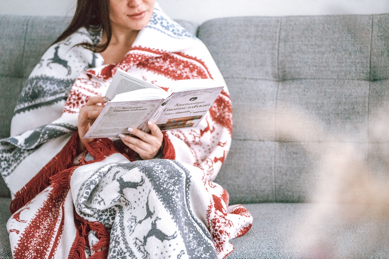 woman reading at home with blanket around her